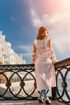 Woman travel sea. Young Happy woman in a long red dress posing on a beach near the sea on background of volcanic rocks, like in Iceland, sharing travel adventure journey