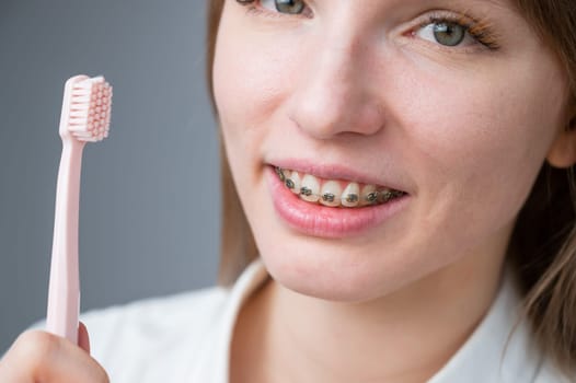 Portrait of a caucasian woman with braces on her teeth holding a toothbrush