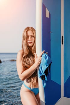 Close up shot of beautiful young caucasian woman with black hair and freckles looking at camera and smiling. Cute woman portrait in a pink bikini posing on a volcanic rock high above the sea