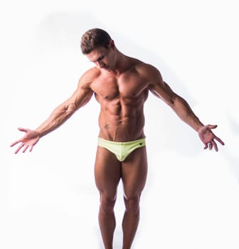 A man wearing only yellow underwear is striking a pose for a photo. He is confidently showcasing his physique while being captured on camera.