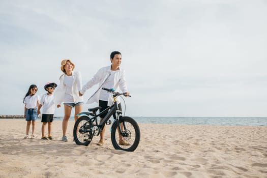 A blissful family stroll on the beach with bicycles in tow parents children and the full happiness of a carefree day by the sea. Family on beach vacation