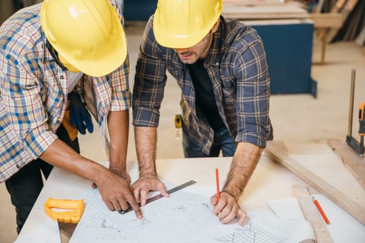 Two carpenter man wear meeting planning job together at carpentry workshop, craftsmen talking on construction plan blueprint, Happy Carpenter's Day