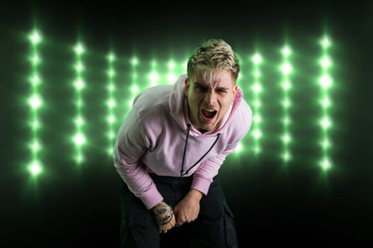 A photograph of a man wearing a pink shirt and black pants, captured with his mouth wide open in a candid moment.