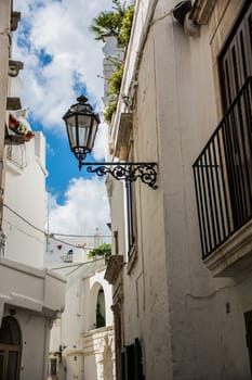 A view of Ostuni, Italy, at night. The White City nestled on a hill overlooking the Adriatic Sea in Puglia, Italy. The photo shows a row of white buildings. The buildings are all different shapes and sizes, but they are all painted white, which gives the town its unique appearance.