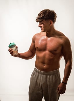 A shirtless man standing while holding a blender or shaker
