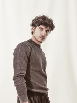 A photo of a man with curly hair standing confidently in front of a plain white background. The man appears relaxed and comfortable, showcasing his unique hairstyle.