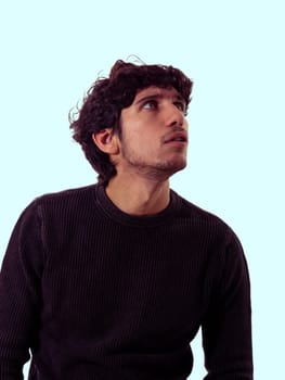 A photo of a man with curly hair wearing a black sweater, looking directly at the camera. The man is standing against a neutral background, showcasing his unique hairstyle and sense of style.