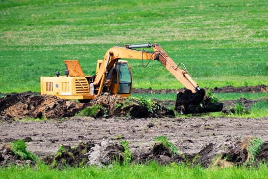 An excavator is digging the ground. Construction work on the field of an agricultural enterprise
