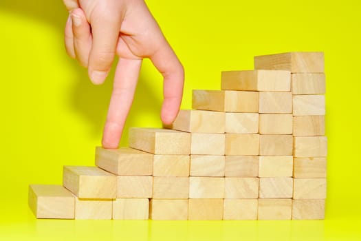 A hand finger walk on stacked wooden block like stairs. Business development and growth concept.