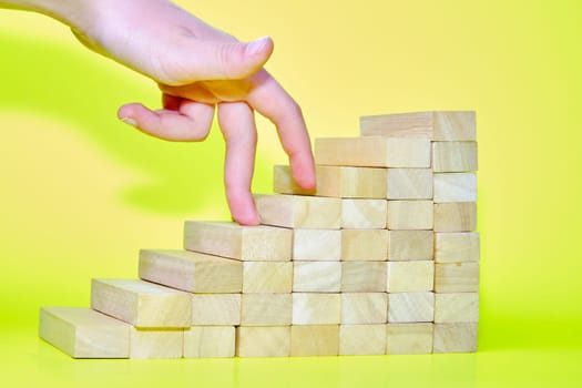 wooden blocks with hand-walking symbolize the concept of stairs to the goal.