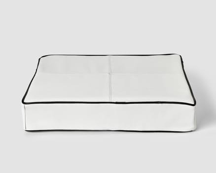 Minimalist soft floor cushion in white leather decorated with contrasting black piping. Stylish item of interior design