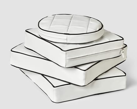 Stack of stylish minimalist square and round seat cushions of different sizes in white genuine leather decorated with black trim. Handmade interior accessories