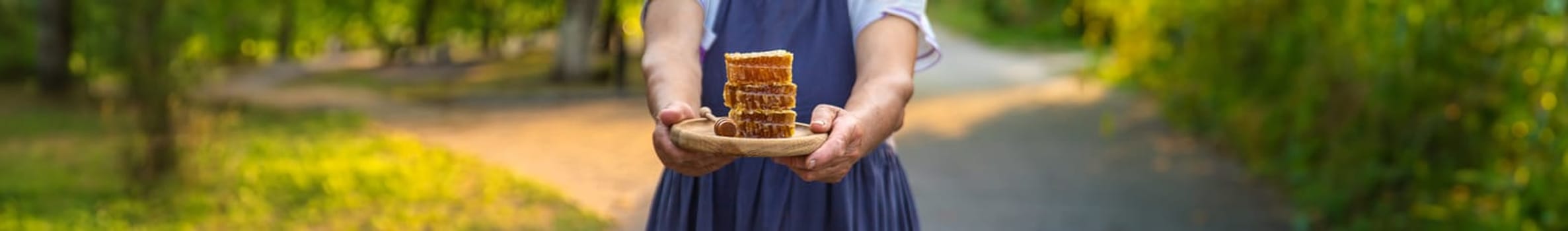 An elderly woman holds honey in her hands, selective focus. People.