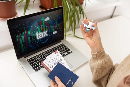 woman holding toy plane, tickets, laptop and taxes.
