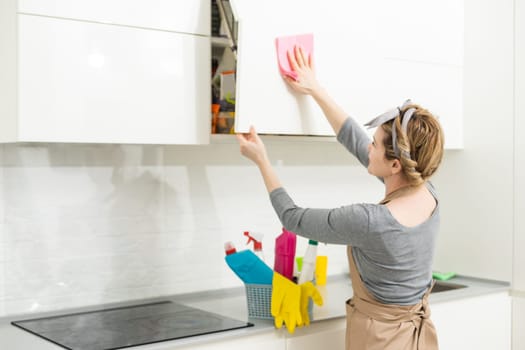 Woman cleaning and polishing the kitchen worktop with a spray detergent, housekeeping and hygiene concept