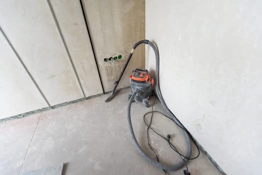 Industrial vacuum cleaner on the dusty floor of construction site. High quality photo