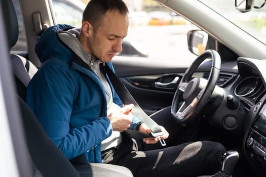 transportation and vehicle concept - man fastening seat belt in car.