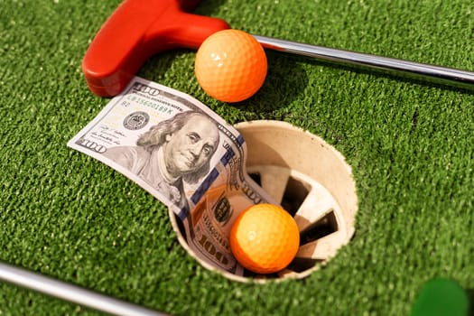 Mini Golf club, ball and money on the artificial grass.