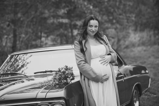 Vejle, Denmark, October 26, 2023: Pregnant woman near a retro car.