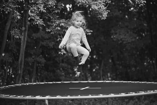 Child jumping on a trampoline in the evening garden in Denmark.