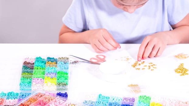 Delicate fingers of a young girl navigate through a treasure trove of bright, multicolored beads, each compartment revealing a new hue to choose from.