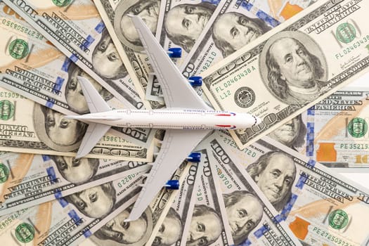 Model passenger aircraft on a background of dollar bills. High quality photo