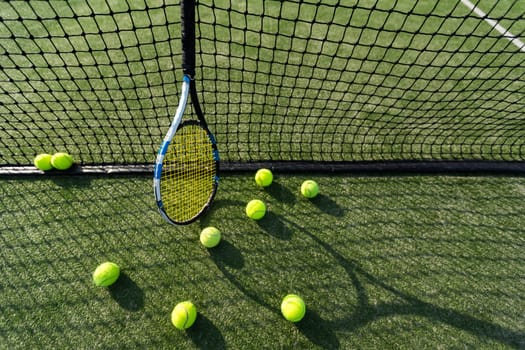 Tennis racket lying on net with tennis ball in hard surface court . High quality photo
