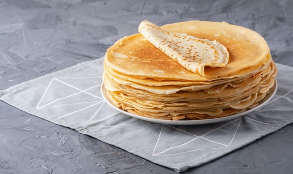 A stack of thin pancakes on a grey table , with copy space for text.