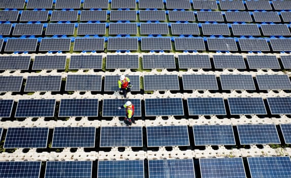 Top view and wind shot of two technician workers maintenance or check system of solar cell panels over the water reservoir as solar farm factory in concept of green energy for good environment.