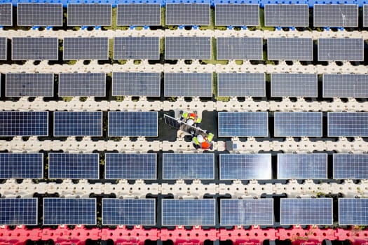 Top view of two technician workers install or set up solar cell panels over the water reservoir as solar farm factory in concept of green energy for good environment.