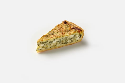 Piece of traditional French quiche with crispy shortbread crust filled with savory custard, cheese and spinach, isolated on white background