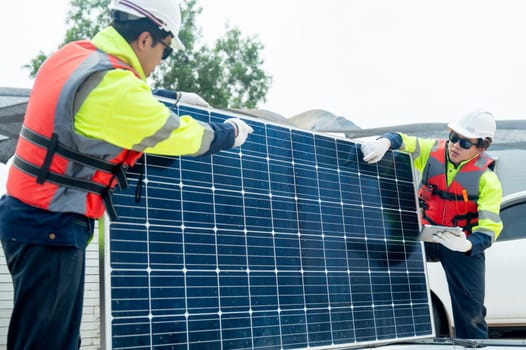 Two Asian professional technician workers hold and discuss about the quality of solar cell panel and they work in workplace area with concept of green energy system.