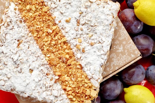 Delicious sweet freshly baked galette with buttery brioche dough and filling of fruit confit sprinkled with crunchy nut streusel, powdered sugar and almond flakes surrounded by ripe plums