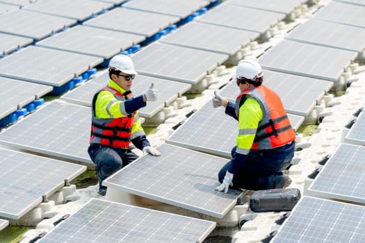 Two technician workers sit together during work with solar panels over water reservoir and show thumbs up express the successful of their work in workplace.