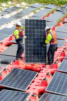 Two professional technician workers stand and hold solar cell panel to check and maintenance the system in concept of green energy power plant for good environment.