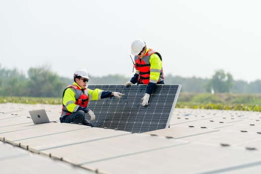 One technician worker sit and point to area of problem and work with co-worker who stand and touch to check the problem of solar cell panel in the network system.