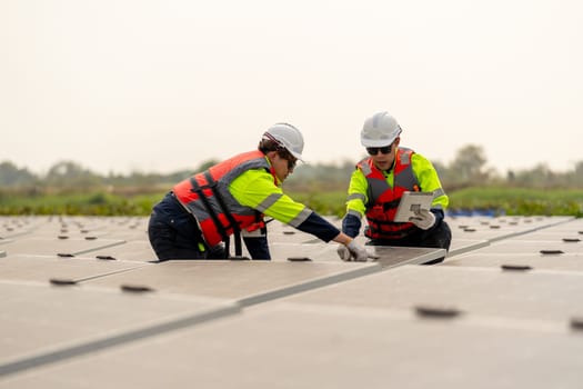 Close up of two technician workers sit and work on process of maintenance solar cell panel network system in concept of green energy power.