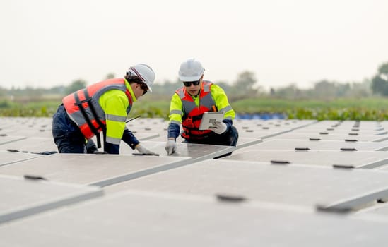 Close up shot of two technician workers sit and work on process of maintenance solar cell panel network system in concept of green energy power.