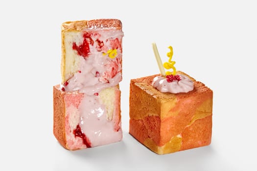 Whole and sliced light, flaky and delicately sweet cube shaped croissants filled with raspberry custard topped with pink icing and candied berries. Modern confectionery in classic French tradition