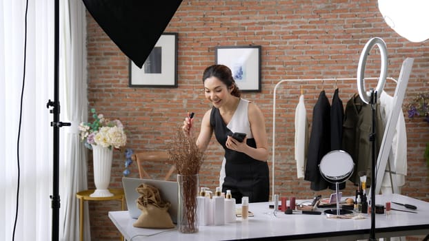 Woman influencer shoot live streaming vlog video review vivancy makeup social media or blog. Happy young girl with cosmetics studio lighting for marketing recording session broadcasting online.