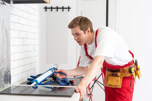 craftsman installs hob in kitchen. Household Appliance Installation Services Concept