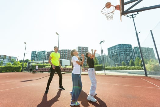 summer holidays, sport and people concept - happy family with ball playing on basketball playground. High quality photo