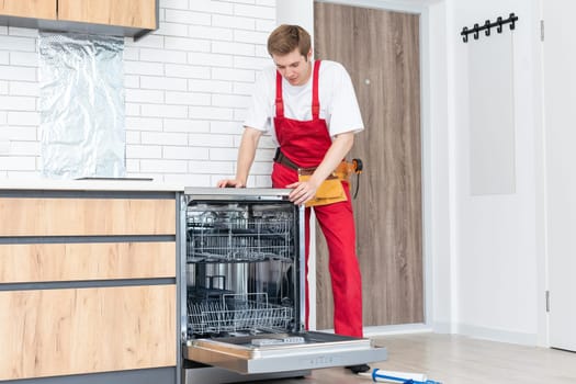 Concept maintenance service of home appliances. Worker cleans filter in the dishwasher. Male repairman checking food residue filters.