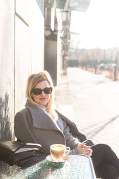 Young caucasian woman business woman drinks coffee at coffee shop terrace. High quality photo