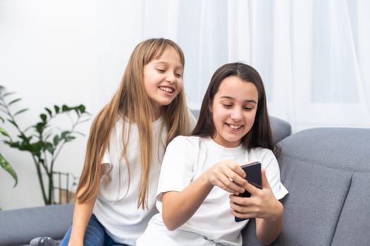 people, technology and friendship concept - happy teenage girls taking selfie with smartphone sitting on sofa at home. High quality photo