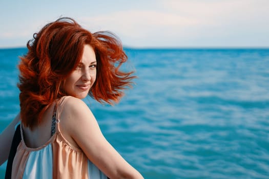 A beachside portrait capturing a young woman glancing over her shoulder with the azure sea as the backdrop.