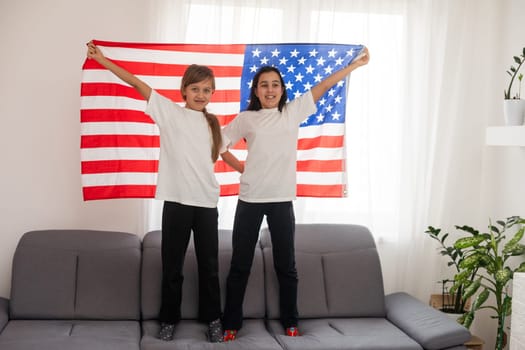 Two sisters with American flag on grey background. High quality photo