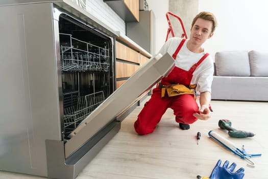 Concept maintenance service of home appliances. Worker cleans filter in the dishwasher. Male repairman checking food residue filters.