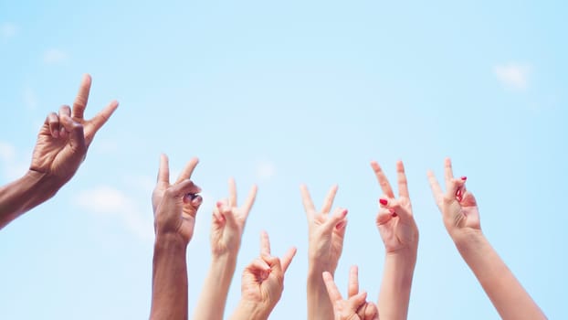 Unrecognizable group of people gesturing victory with the arms raised in the air, with copy space