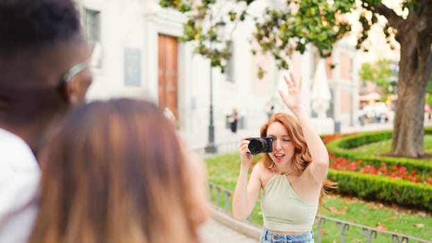 Woman with a camera organising a group of friends to take a photo int he street